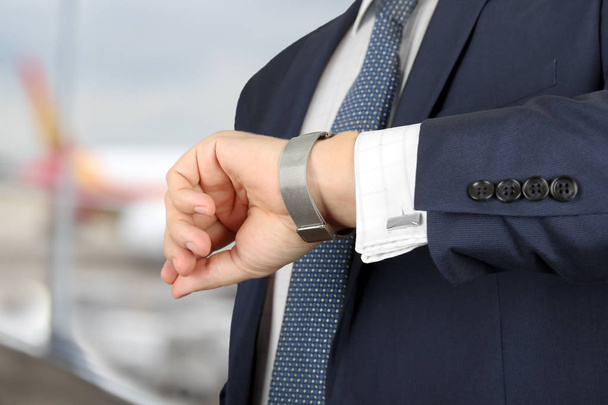  empresário verificando o tempo em seu relógio no aeroporto
 - Foto, Imagem