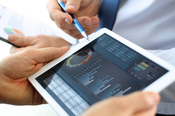Коллеги по бизнесу работают и анализируют финансовые показатели на цифровом планшете
 - Фото, изображение