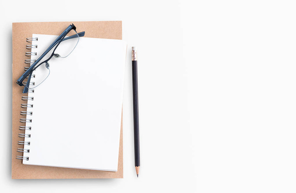 Cuaderno en blanco con lápiz y anteojos sobre fondo blanco
 - Foto, Imagen