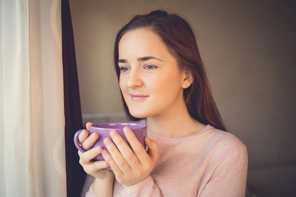 Young Woman enjoying cup of tea in the morning near window - Fotoğraf, Görsel