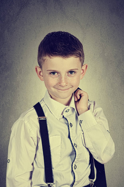 Glimlachend jongetje bedrijf dragen kostuum met bretels - Foto, afbeelding