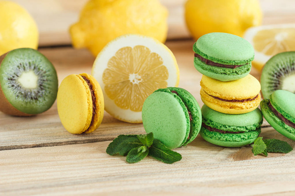 Green and yellow french macarons with kiwi, lemon and mint decorations - Фото, зображення