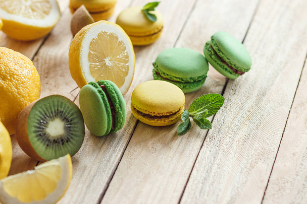 Green and yellow french macarons with kiwi, lemon and mint decorations - Foto, Imagen