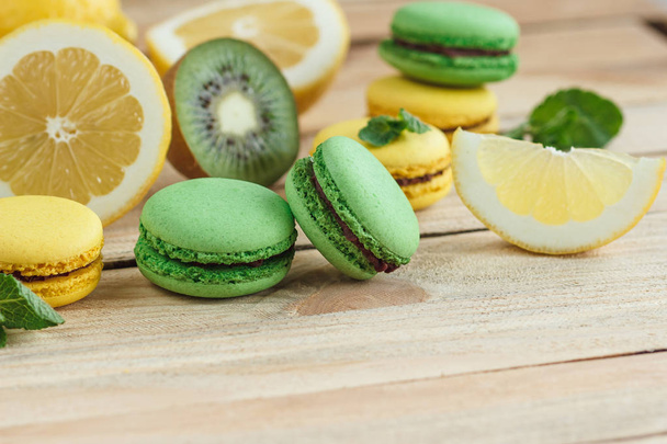 Green and yellow french macarons with kiwi, lemon and mint decorations - Zdjęcie, obraz