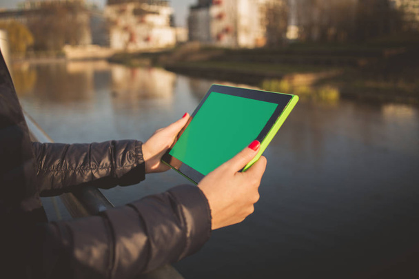 Mujer, estudiante sosteniendo el uso de tableta en un parque de la ciudad cerca del río
 - Foto, Imagen