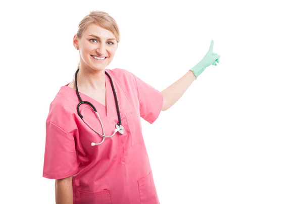 Vriendelijke medisch verpleegkundige dame glimlachend wijzende copyspace - Foto, afbeelding