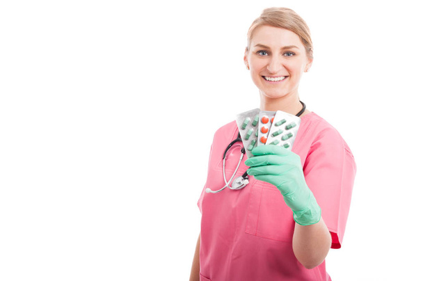 Friendly medical nurse lady smiling showing tablet blister - Foto, afbeelding