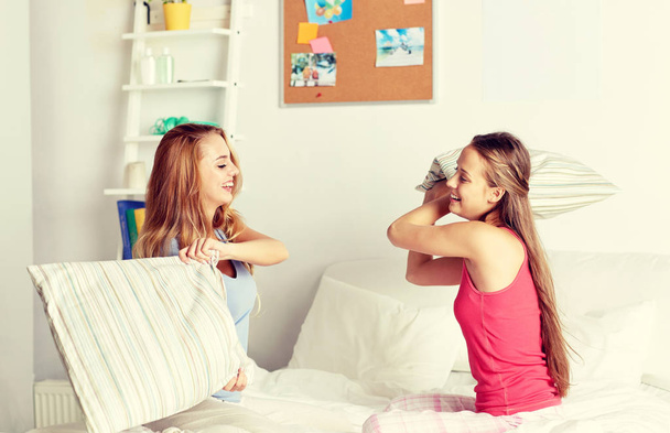 happy teen girl friends fighting pillows at home - Fotografie, Obrázek