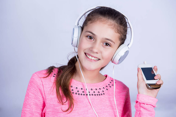 Smiling Little girl enjoying music in headphones at home relaxing - Valokuva, kuva
