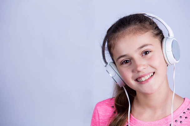 Smiling Little girl enjoying music in headphones at home relaxing - 写真・画像