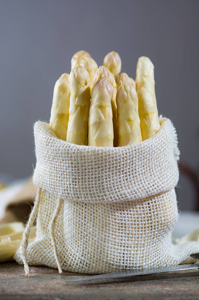 Άνοιξη - φρέσκα λευκά σπαράγγια σε λινάτσα σάκος σε γρανίτη  - Φωτογραφία, εικόνα