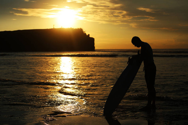 Surfer au coucher du soleil au bord de la mer
.  - Photo, image
