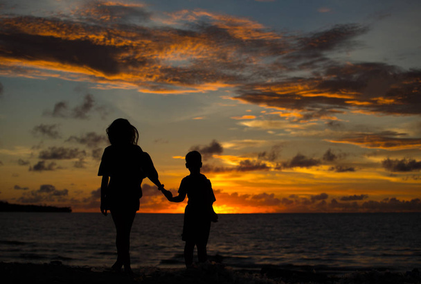 Mutter und Sohn bei Sonnenuntergang am Meer. - Foto, Bild