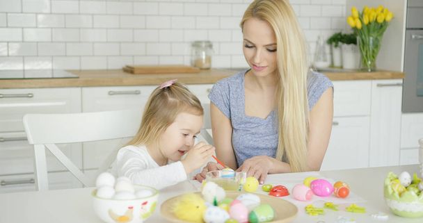 Young female and little girl painting eggs - 写真・画像
