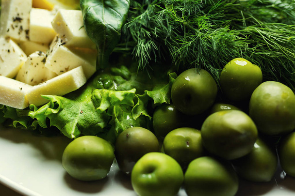 Olives, brynza and greens on a plate,Fresh salad with bryndza, olives,plate of soft cheese (feta and bryndza),Green olives in the bowl - Photo, Image