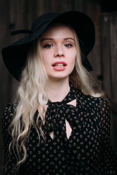 Beautiful attractive and stylish girl wearing black hat standing posing in city. Nude makeup, best daily hairstyle and great fashion glamour country style. - Fotografie, Obrázek