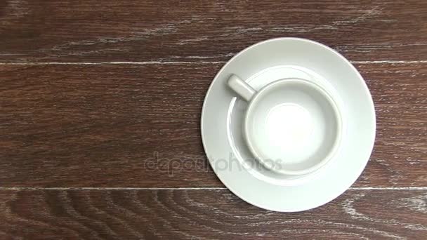 Lege witte koffie beker met schotel op bruin tafel - Video