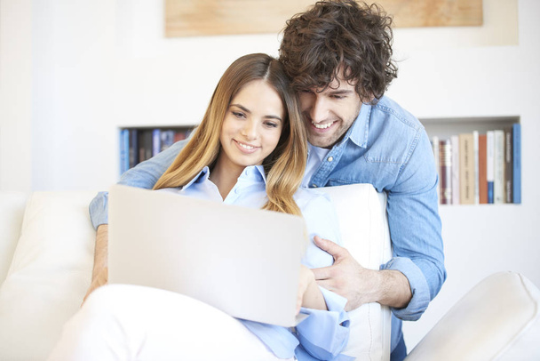 couple sitting on couch with laptop - Foto, imagen