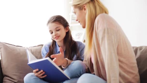 happy girl with mother reading book at home - Filmagem, Vídeo