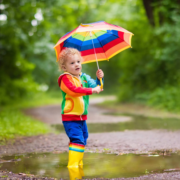 Kind spielt im Regen unter Regenschirm - Foto, Bild