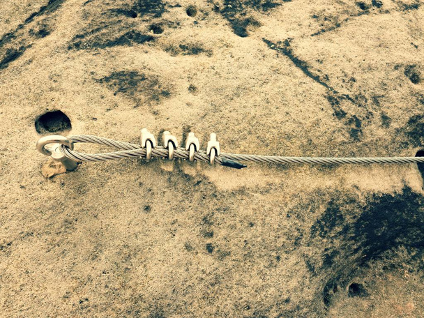 Eisen gedrehtes Seil, das zwischen Felsen gespannt wird, um Klettersteige zu besteigen. Seil im Fels befestigt - Foto, Bild