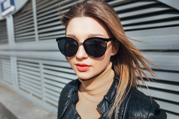 Fashion portrait pretty woman in black rock style in sunglasses over gray background in city - 写真・画像