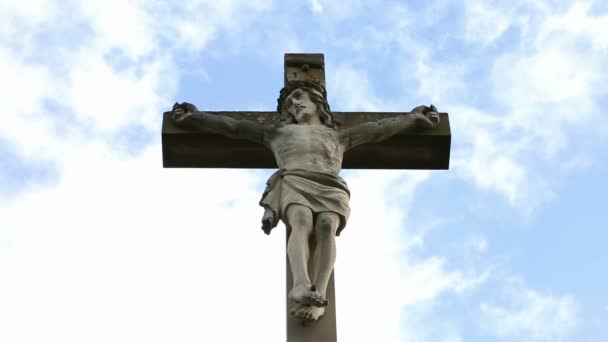 primer plano de la cruz de piedra con Jesús y el cielo azul con nubes
 - Metraje, vídeo