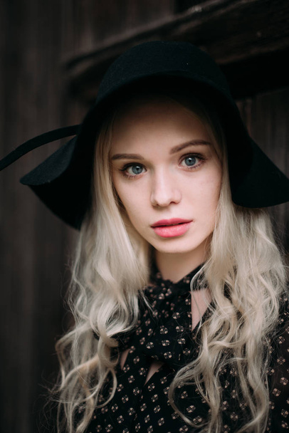 Beautiful attractive and stylish girl wearing black hat standing posing in city. Nude makeup, best daily hairstyle and great fashion glamour country style. - Photo, Image