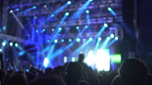 Excited music fans dancing at concert in shimmering lights, waving hands - Footage, Video