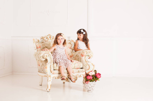 Two girls sits in a magnificent ancient armchair - Fotó, kép