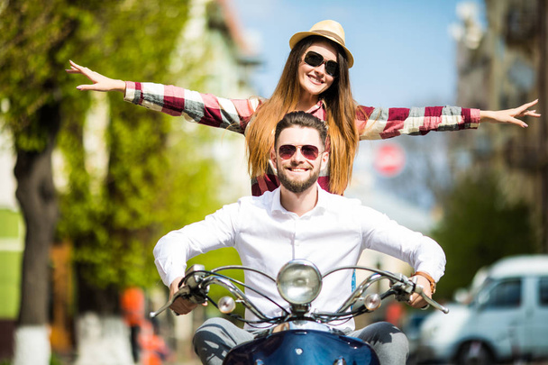 幸せな女の腕を上げると、笑顔ながら一緒に美しい若いカップル乗りスクーター - 写真・画像