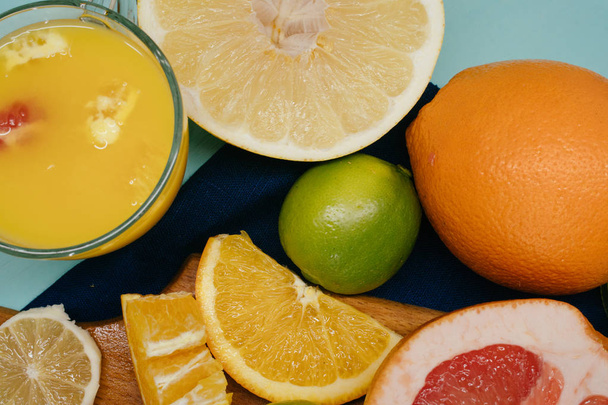 Citrinos, laranjas, limões, limas, toranja, pomelo sobre placa vintage, limonada e suco em um copo de vidro sobre um fundo turquesa
 - Foto, Imagem