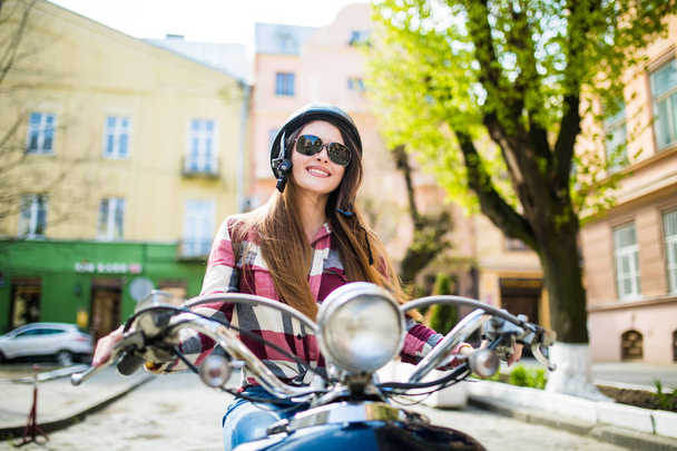 Приваблива щаслива жінка на скутері в літній день на міській вулиці
 - Фото, зображення