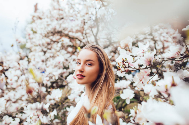 portrait of young woman surrounded with magnolia tree - Foto, Imagen