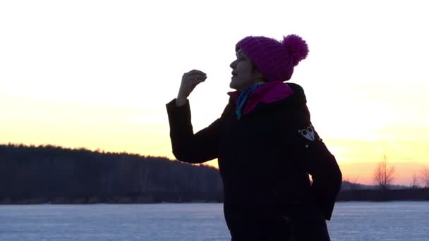 Mooie vrouw stuurt een kus en linker glimlachend in de achtergrond van een winterlandschap - Video