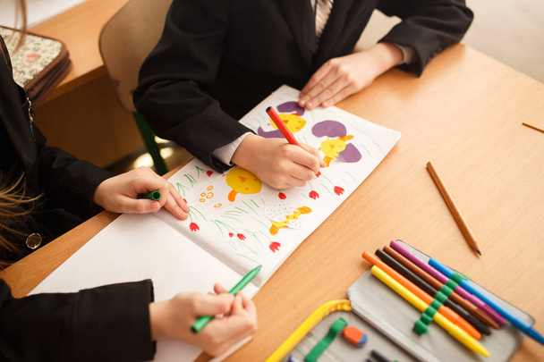Kind zeichnet Filzstifte. Ein kleines Kind hält einen blauen Filzstift in der Hand und zeichnet. eine Kinderzeichnung, ein Satz farbiger Filzstifte auf einem Holztisch. - Foto, Bild