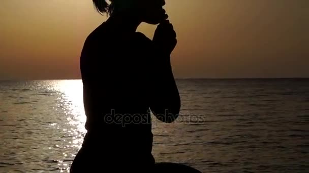 Siluetti tyttö rukoilee kukkulalla auringonlaskun aikana
 - Materiaali, video