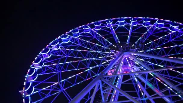 Diabelski Młyn niebieski neon światła na ciemnym tle, część Ferris wheel z niebieskie podświetlenie na tle Czarnego nieba w nocy. Diabelski Młyn w nocy. Diabelski młyn z Multi-kolorowe - Materiał filmowy, wideo