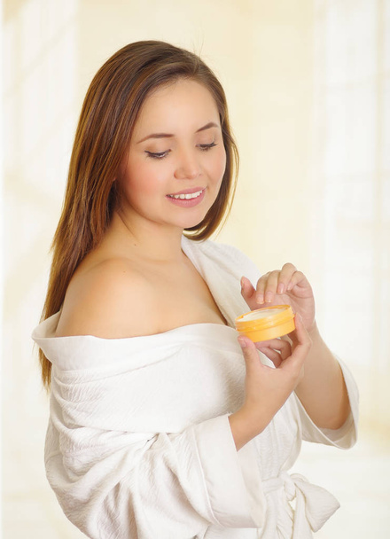 Beautiful smiling young woman adding a cream body over her shoulder - Photo, Image