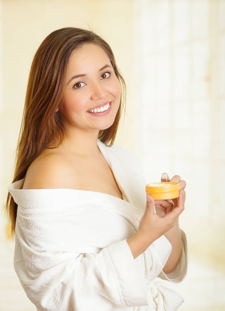 Beautiful smiling young woman holding a cream body - Foto, afbeelding