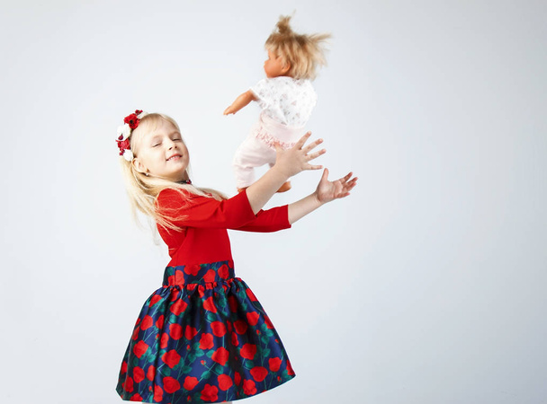 Pequeña niña feliz jugando a una muñeca, en un blanco
 - Foto, imagen