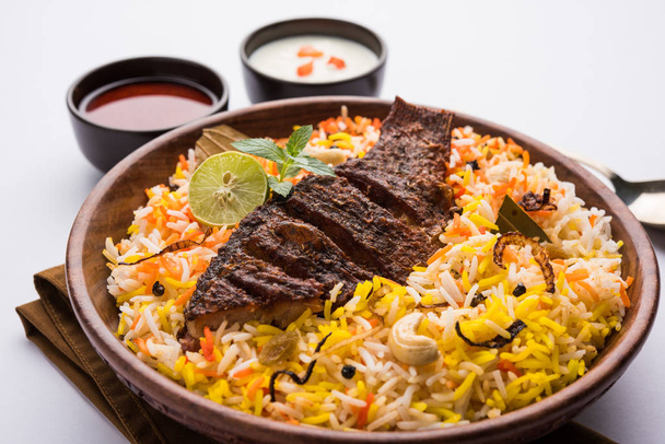 Fish Biryani or fish Rice - Popular Indian non-vegetarian recipe made of fish marinated with Indian spices fresh herbs and cooked with Basmati rice, selective focus - Photo, Image