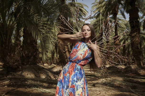 The girl in a beautiful dress model posing in the palms. - Foto, imagen