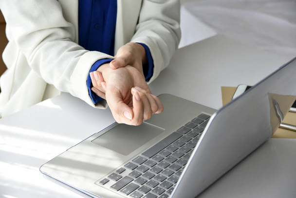 Woman holding her wrist pain from using computer. - Zdjęcie, obraz