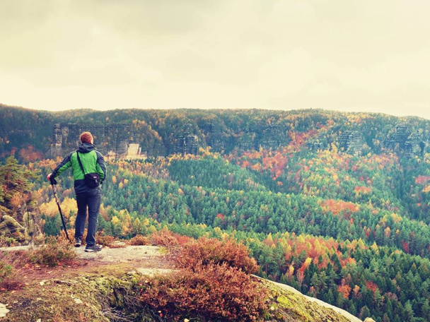 Zencefil saç adam akıllı telefon fotoğraflarla sonbahar Vadisi üzerinde kayalık tepe alır. - Fotoğraf, Görsel