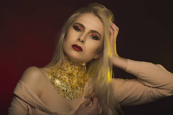 Femme glamour avec un maquillage lumineux et une feuille d'or sur son cou
 - Photo, image