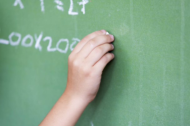 Caucasian child hand writing at chalkboard - 写真・画像