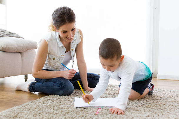 Beautiful young mother and her son drawing at home. - Valokuva, kuva