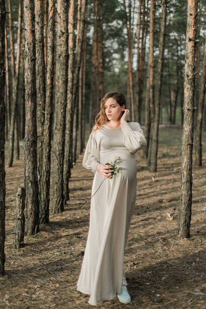 zwangere vrouw op pad in bos - Foto, afbeelding