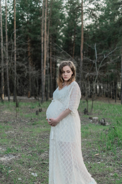pregnant woman on lawn in forest - Фото, изображение